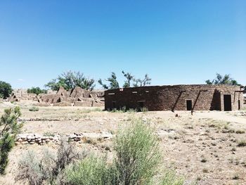 Abandoned building on field against clear blue sky