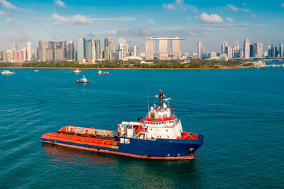 Nautical vessel on sea by buildings against sky in city