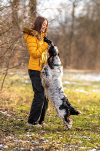 Portrait of young woman with dog on field