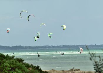 People kiteboarding in sea against clear sky