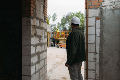 Foreman builder engineer worker looking at large building construction site sunny day hard work