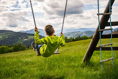 Rear view of boy on swing in playground