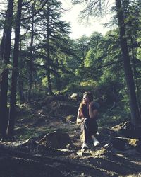 Woman standing by tree in forest