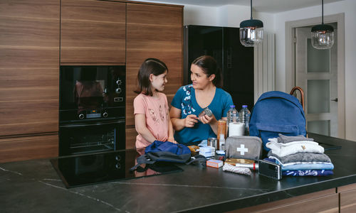 Mother explaining to her daughter how to prepare emergency backpack