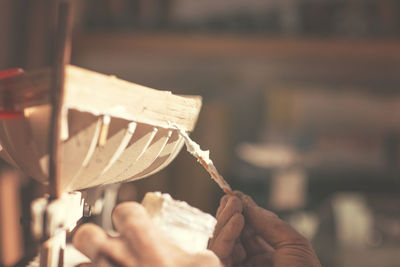 Close-up of man working on wooden boat model