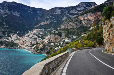 Empty road leading towards mountains at sea shore