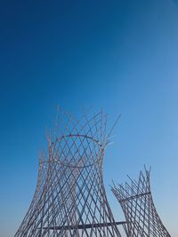 Low angle view of rollercoaster against clear blue sky