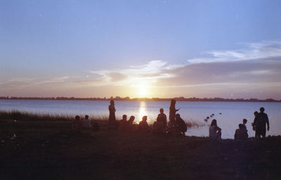 Silhouette people on beach against sky