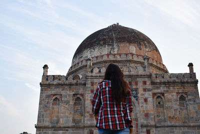 Rear view of woman standing at historical building against sky