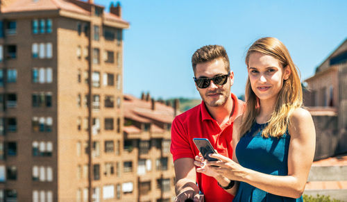 Portrait of young woman using mobile phone in city