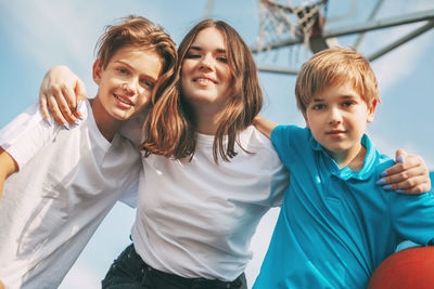 Low angle portrait of smiling siblings standing sky