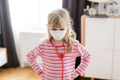 Portrait of girl wearing mask while standing at home