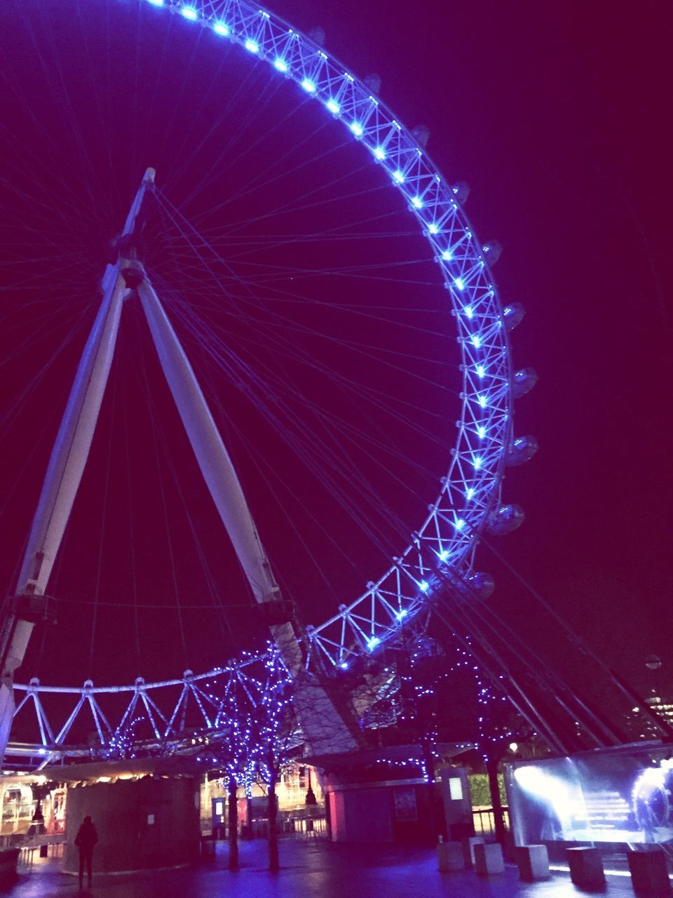 illuminated, night, arts culture and entertainment, ferris wheel, amusement park, amusement park ride, low angle view, built structure, architecture, sky, motion, long exposure, lighting equipment, fun, building exterior, multi colored, city, celebration, clear sky, glowing