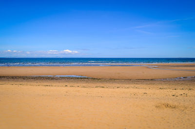 Scenic view of beach against blue sky