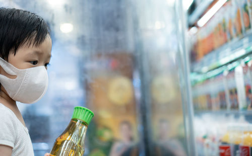 Close-up portrait of boy holding bottle in store