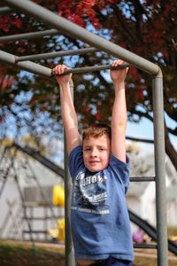 Portrait of boy hanging on railing in playground