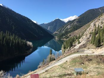 Scenic view of lake and mountains against clear blue sky