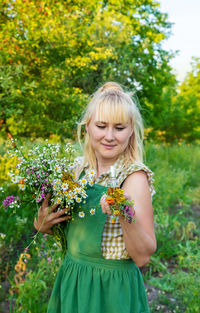 Portrait of smiling young woman standing amidst plants