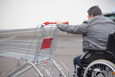 Physical disabled person in a wheelchair pushing shopping cart