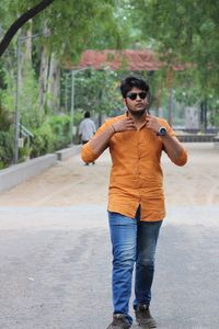 Full length of young man wearing sunglasses while walking on road