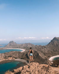 Full length of woman standing on mountain against blue sky