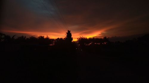 Silhouette trees on landscape against sky at sunset