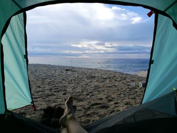 Low section of woman by sea against sky