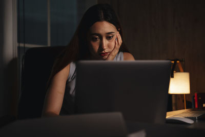 Depressed girl using laptop sitting at home