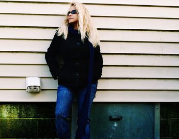 Young woman standing against wall