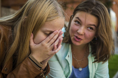 Teenage girl with sad sister sitting outdoors