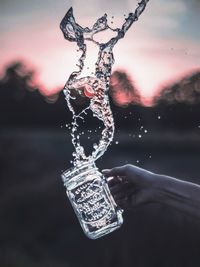 Close-up of hand holding water against sky