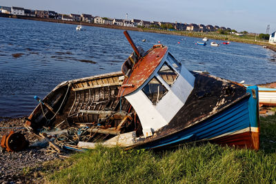 Abandoned boat moored on beach against sky