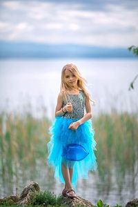 Full length of girl standing on rock against sea