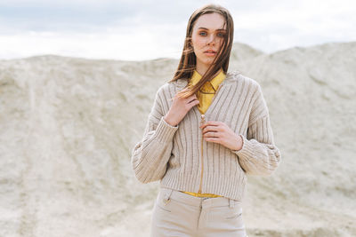 Fashion beauty young woman with long hair in knitted cardigan on desert background, autumn outfit