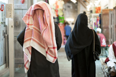 Rear view of woman wearing burkas walking on footpath in city