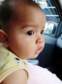Close-up portrait of cute baby girl in car