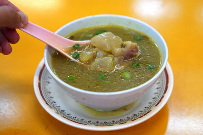 Close-up of hand holding soup in bowl