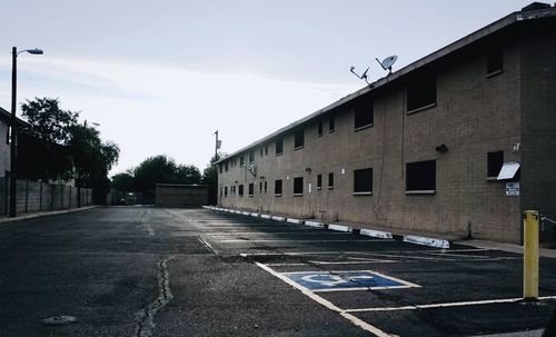 Empty road amidst buildings against sky in city