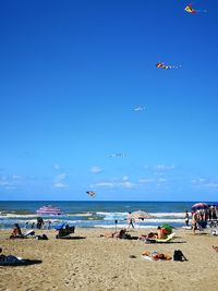 People on beach against blue sky