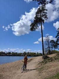 Man riding bicycle on street against sky