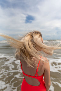 Midsection of woman at beach against sky