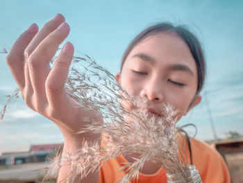 Close-up of woman holding plants against sky