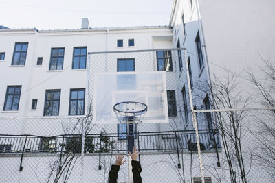 Low angle view of person playing basketball against building