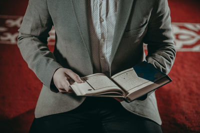 Midsection of man reading book