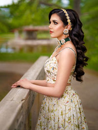 Young woman looking away while standing outdoors