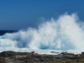 Waves splashing on shore against sky
