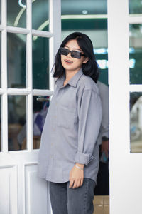 Portrait of young woman wearing sunglasses while standing outdoors