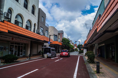 Cars on road amidst buildings in city against sky