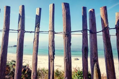 Close-up of wooden posts on beach against sky