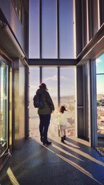 Rear view of woman with daughter standing in building